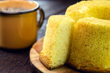 Sliced ​​Brazilian corn cake made with a type of corn flour (Fuba or Fubá), with a hot coffee mug in the background. Typical Brazilian snack in the state of Minas Gerais.