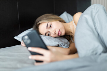 Young woman texting while lying on a bed at home