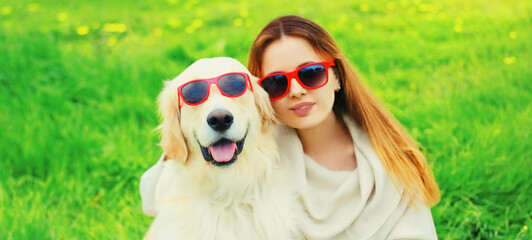 Portrait girl with her Golden Retriever dog wearing a sunglasses on green grass in the park