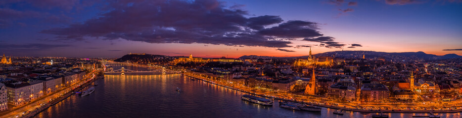 Panoramic aerial drone shot of lighted quai of Buda Hill by Danube in beautiful Budapest sunset