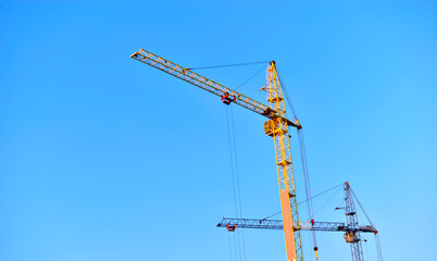 Yellow construction tower crane in the city against the sky © Lushchikov Valeriy