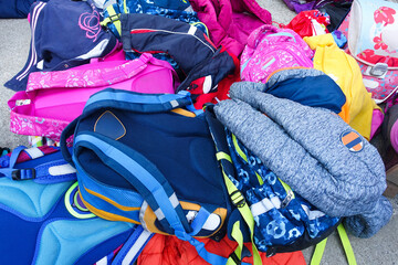 Group of various colorful school bags thrown on the ground. Many different children bags left on schoolyard's floor during school break, close up. Background of colorful backpacks