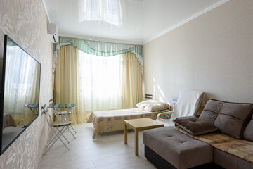 Fototapeta na wymiar Spacious bedroom interior with large sofa and bed, and glossy stretch ceiling