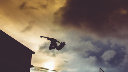 Silhouette of a skateboarder jumping from a vert, sky
