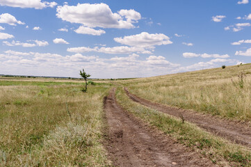 A dirt road passing through a field in a picturesque location.