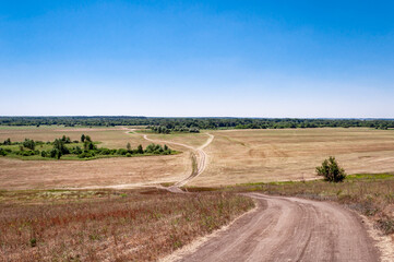Obraz premium A dirt road passing through a field in a picturesque location.
