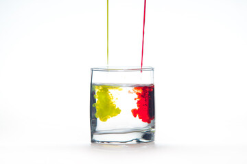 A glass of water on a white background with red and yellow paint.