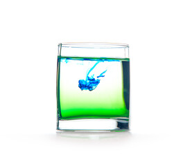 Glass with water on a white background with blue paint.