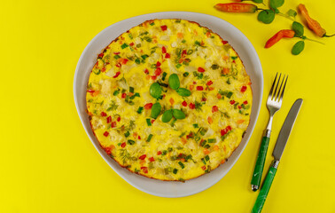 Breakfast with vegetable omelette on yellow background.