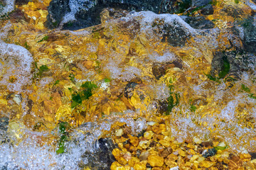 Abstract moving water on beach rocks.. Soft focus.