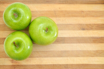 green apple sit on a worn butcher block cutting board
