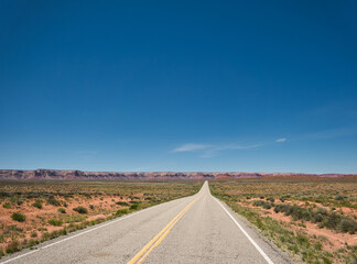 Eine gerade und ewig lange Straße vor den Bergen