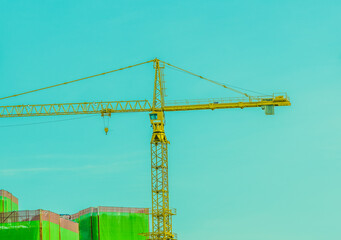 Large yellow crane against blue sky.