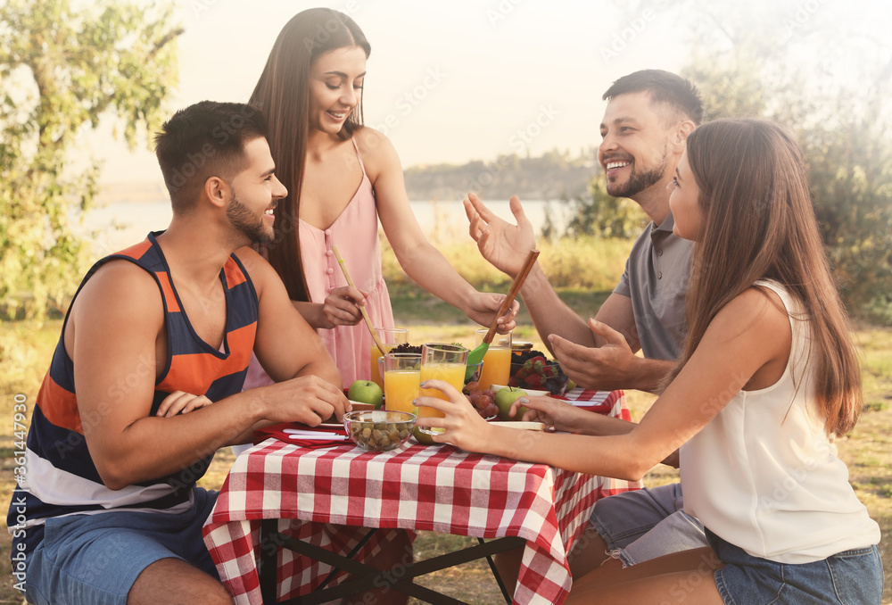 Poster Happy young people having picnic at table in park