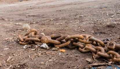 Closeup of large rusty chains laying on the ground