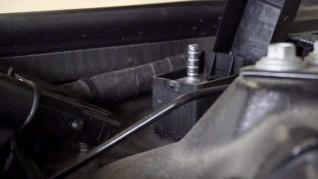 Car mechanic is connecting battery charger with leads to special charging points on the car for programming.