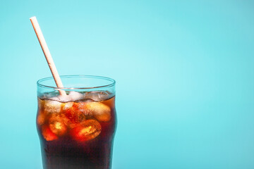 Coffee with ice in a glass cup with tube on a blue background, a copy of the space
