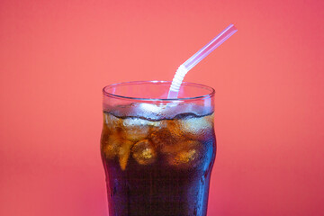 Ice coffee in a glass glass with tube on a dark pink background, a copy of the space