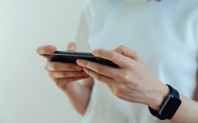 Closeup of young woman hand holding smartphone and chatting with friends at social network.