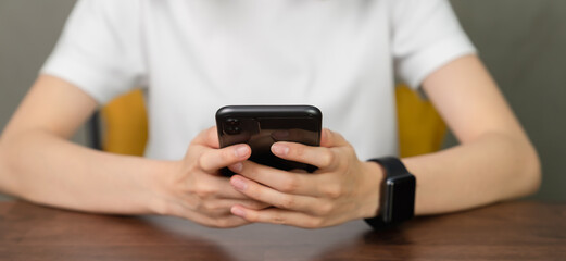 Closeup of young woman hand holding smartphone and chatting with friends at social network.