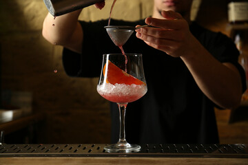 Bartender preparing fresh alcoholic cocktail at bar counter, closeup