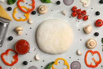 Flat lay composition with dough and fresh ingredients for pizza on grey marble table