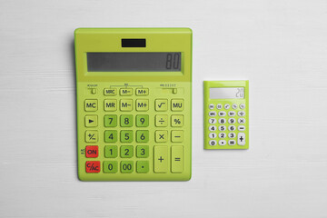 Different calculators with numbers 80 and 20 on white wooden background, flat lay. Pareto principle...