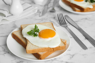 Tasty fried chicken egg with bread and parsley on white marble table, closeup
