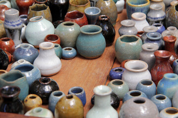 Fototapeta na wymiar Miniature colored jars made of ceramics on wooden table