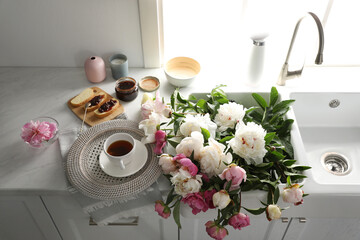 Beautiful peonies and breakfast on kitchen counter, above view