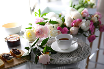 Beautiful peonies and breakfast on table indoors