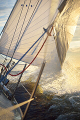 White sailboat in an open sea at sunset. Single handed sailing a 34 ft yacht. Close-up view of the...