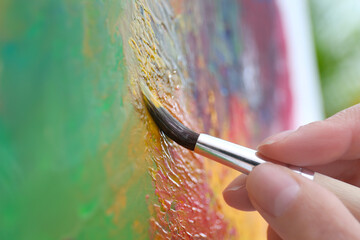 Artist painting on canvas with brush, closeup