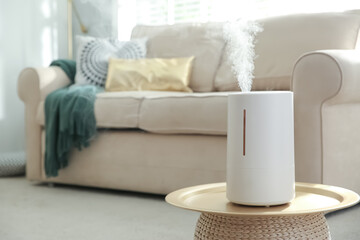 Modern air humidifier on table in living room. Space for text