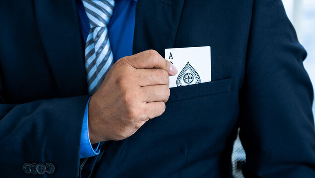 A business man's hand is holding an ace card out of a suit pocket, at a magic poker show. Gambling concept