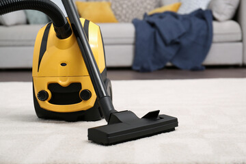 Modern yellow vacuum cleaner on carpet indoors, space for text
