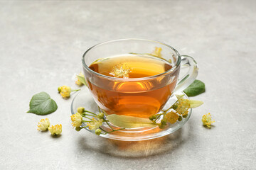 Cup of tea and linden blossom on light grey table