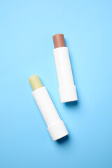 Hygienic lipsticks on light blue background, flat lay