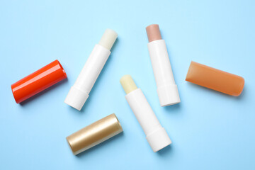 Hygienic lipsticks on light blue background, flat lay