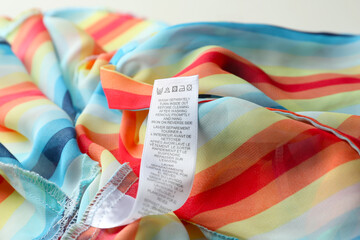 Clothing label with care instructions on colorful striped garment, closeup