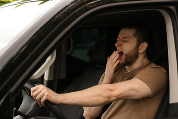 Tired man yawning while driving his modern car - obrazy, fototapety, plakaty
