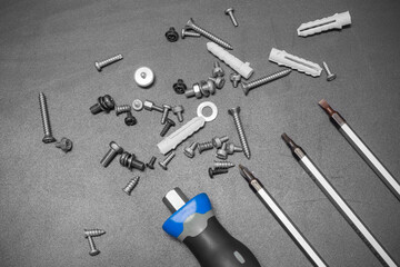 Several screwdriver and screws set are spread on the black surface.