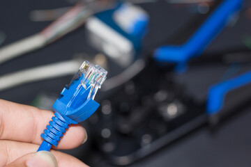 The hand is holding the blue RJ45 Cat6 cable.