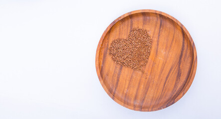 Theme of diet and weight loss on a white background. buckwheat in a wooden plate is laid out in the shape of a heart.