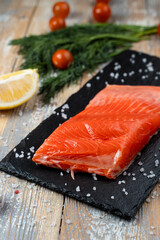 Fresh trout fillet steak on blackstone background with sea salt around, market catalogue photo