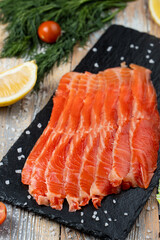 Trout sashimi on a stone board with lemon and salt around