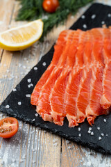 Trout sashimi on a stone board with lemon and salt around
