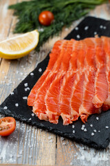 Close up of red fish sashimi slices on a stone background with lemon and salt around