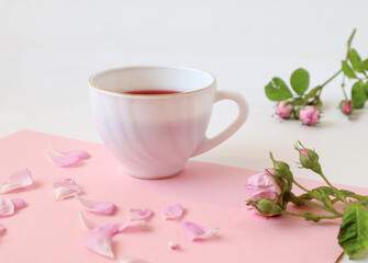 Fototapeta na wymiar A Cup of morning tea with branches and rose petals on a pastel background, side view, close-up, place for the inscription-the concept of good morning and good mood.