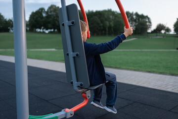 Street workout equipment, outdoor sport. Boy in a sport playground doing workout exercises outdoor